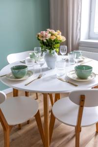 a white table with a vase of flowers on it at Apartament Miętowy Kwidzyn in Kwidzyn +32 photos