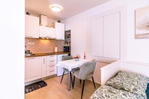 a kitchen with white cabinets and a table and chairs at Studio apartman Relota in Kaštela +11 photos