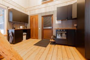 a kitchen with black cabinets and a wooden floor at Atpūtas māja Upeskrasti in Zosuļi
