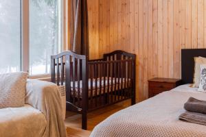 a baby crib in a room with a window at Atpūtas māja Upeskrasti in Zosuļi