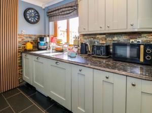 a kitchen with white cabinets and a counter with a microwave at Pentre Country Studio in Wrexham