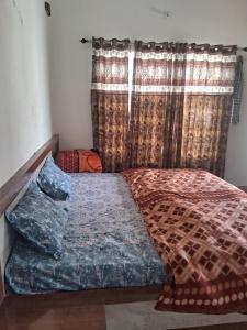 a bed sitting in a room with a window at Nilkanth gest hause in Mukteshwar