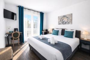 a bedroom with a large white bed with blue pillows at Logis Hôtel Blue Garden in Grandvillers