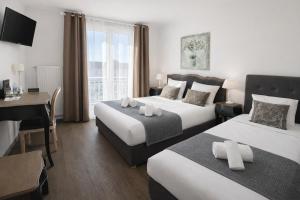 a hotel room with two beds and a desk at Logis Hôtel Blue Garden in Grandvillers