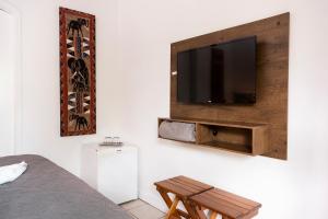 a bedroom with a flat screen tv on a wall at Chalés Kalimmera in Ilhabela