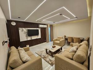 a living room with couches and a flat screen tv at Salalah Apartment in Cairo