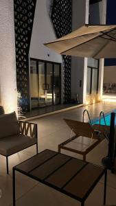 a patio with a pool and chairs and an umbrella at اصيلة فيلا Asilah Villa in Buraydah