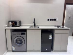 a kitchen counter with a sink and a washing machine at دار مسك الفندقية in Medina