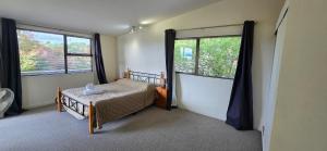 a bedroom with a bed and two large windows at Cagou's Bach in Kuratau