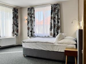 a bedroom with a bed with black and white curtains at Hotel U Vlašského Dvora in Kutná Hora +23 photos