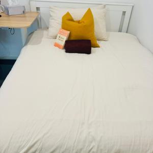 a white bed with yellow pillows and a book on it at Casa de Burgh in Turner