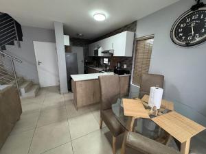 a kitchen with a table and a clock on the wall at Kheniyas Haven in Nelspruit