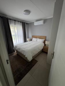 a bedroom with a white bed and a window at Kheniyas Haven in Nelspruit
