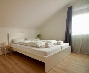 a large white bed in a room with a window at Helle Ferienwohnung im Schwarzwald - 2 Schlafzimmer - WLAN - Holzapfel Apartments in Villingen-Schwenningen
