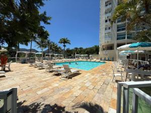 a swimming pool with lounge chairs and a building at Camboflat in Niterói