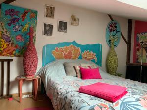 a bedroom with a bed with pink pillows and vases at Maison de charme du 18 e s de centre ville in Sablé-sur-Sarthe