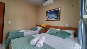 a bedroom with two beds with towels on them at Casa de Temporada D'Amaro in Santo Amaro