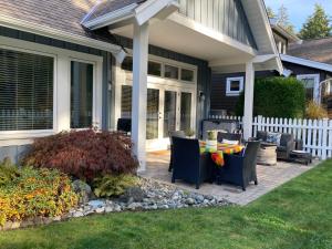 a patio with a table and chairs on a house at Qualicum Landing Coastal Cottage in Qualicum Beach +3 photos
