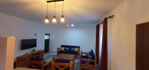 a living room with blue chairs and a television at TajiS Diani Chic 1 BR with swimming pool in Diani Beach