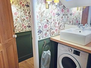 a bathroom with a washing machine and a sink at Freshwater Barn in Benenden