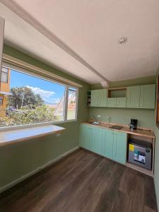 a kitchen with green cabinets and a large window at Naab apart complex in Panajachel