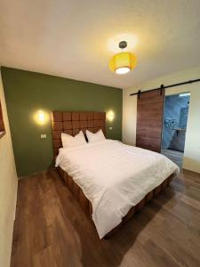 a bedroom with a large white bed with a green wall at Naab apart complex in Panajachel