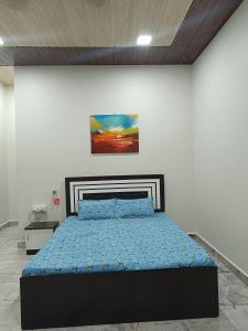 a bedroom with a bed with a painting on the wall at Varsha farm house in Guhagar