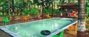 a swimming pool in a garden with chairs and tables at Varsha farm house in Guhagar