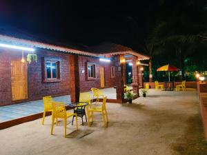 a patio with yellow chairs and a table and a house at Varsha farm house in Guhagar