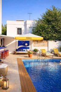 a swimming pool with a yellow umbrella and chairs at Kavala Hotel Bodrum in Bodrum City