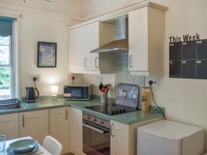 a kitchen with white cabinets and a stove top oven at North Cottage in Lowestoft