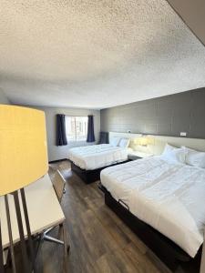 a hotel room with two beds and two tables at Deluxe Inn in Mauldin +2 photos