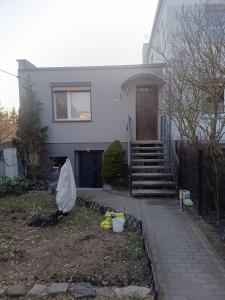 a white house with a porch and stairs to it at Kawalerka Perzycka in Poznań