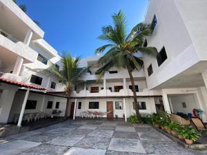 a large building with palm trees in the courtyard at Costa Ayala - Suites & Bungalows in Los Ayala