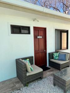 a porch with two wicker chairs and a door at Orquídea de la Paz in Coco