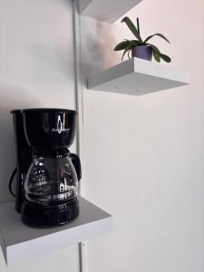 a black coffee maker on a shelf with a plant at Orquídea de la Paz in Coco