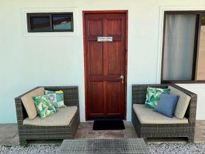 two wicker chairs sitting in front of a door at Orquídea de la Paz in Coco
