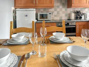 a wooden table with plates and bowls and wine glasses at Brada View in Bamburgh +9 photos