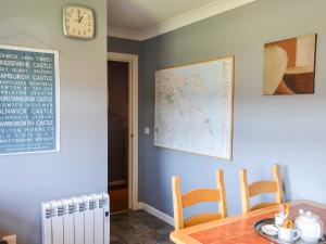 a dining room with a table and a clock on the wall at Brada View in Bamburgh