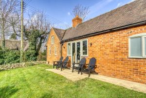 a group of chairs sitting outside of a brick house at Gleanings Cottage in Bredon