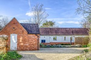 a red brick house with a white garage at Gleanings Cottage in Bredon