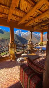 a porch with chairs and tables and a view of mountains at Toubkal Ecolodge in Imlil