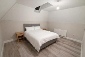 a bedroom with a white bed and a wooden floor at 5 Bedroom Home Monaghan Town in Monaghan