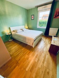 a bedroom with a bed and a wooden floor at Be My Guest - Proche Disneyland Paris in Quincy-Voisins +15 photos
