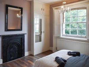 a bedroom with a fireplace and a mirror on the wall at North Cottage in Lowestoft