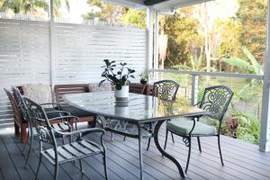 a glass table and chairs on a porch with a table at Enchanted Garden, 3 bedrooms in Sandstone Point +75 photos