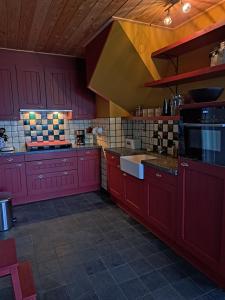 eine große Küche mit roten Schränken und einer Spüle in der Unterkunft Dereshoeve in Bunschoten + 14 Fotos