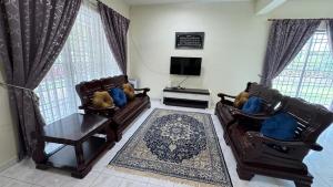 a living room with two couches and a tv at De'Bestari Homestay in Ipoh