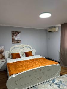 a bedroom with a white bed with orange sheets and pillows at Joy in Atyrau
