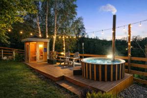 a hot tub on a wooden deck with a gazebo at Căsuța Melimi cu piscină încălzită, ciubăr și saună in Râșca